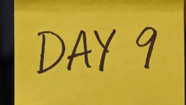 A yellow sticky note that reads DAY 9, held up between two fingers.